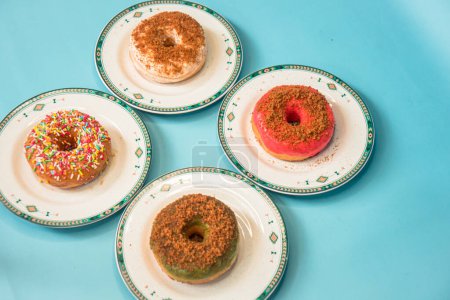 Téléchargez les photos : Donuts made by a home industry with the basic ingredients of palm sugar with various kinds of toppings such as chocolate, strawberries, green tea, and sprinkles. photographed flat served on a plate and a turquoise background - en image libre de droit