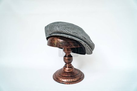 Téléchargez les photos : Détail d'une casquette scale ou d'une casquette plate, avec motif à chevrons en tweed noir et blanc monté sur une tête de mannequin en bronze sur un fond blanc - en image libre de droit