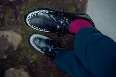 Téléchargez les photos : Jeune homme assis et portant des baskets creepers en cuir véritable noir. Ces chaussures décontractées mais élégantes sont faites à la main par un cordonnier à la maison, parfait pour traîner par une journée ensoleillée - en image libre de droit