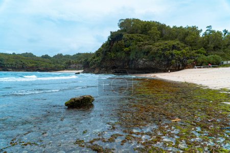 Foto de Una playa escondida que todavía está muy vacía de turistas en el distrito Pacitan, provincia de Java Oriental, Indonesia, que tiene arena blanca y olas encantadoras. La playa con una vista muy hermosa por la mañana - Imagen libre de derechos