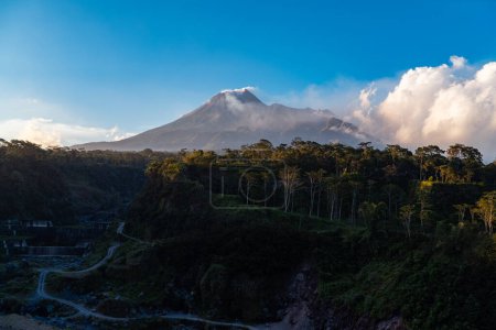 La belleza del monte Merapi al atardecer antes de que oscurezca con un acantilado de lava fría fluye justo en frente de él. Monte Merapi se ve detallado en un día claro con cielo azul y nubes a su lado