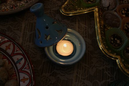 A burning wax candle stands on the table.