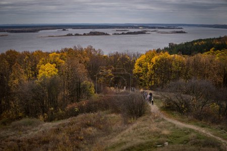 Panoramic view of yellow trees, a wooden hut and the river on an autumn cloudy day.