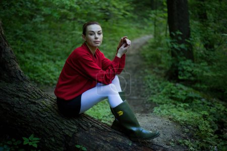 Girl in rubber boots posing in a spring forest, surrounded by blossoming trees and vibrant greenery, exuding the essence of nature's renewal.
