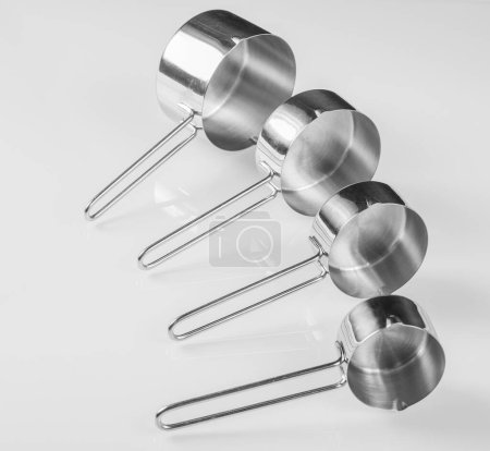 Photo for Kitchen utensils.Small stainless steel ladle on glass white background. - Royalty Free Image
