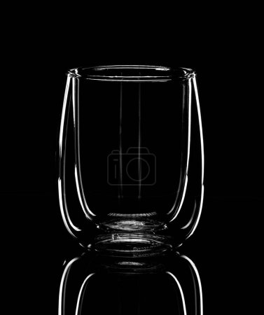 Téléchargez les photos : Minimalisme, la silhouette lumineuse d'un verre pour latte se reflète dans une table miroir noire. Photo monochrome - en image libre de droit