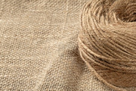 A ball of coarse textured jute threads on a burlap napkin. Close up