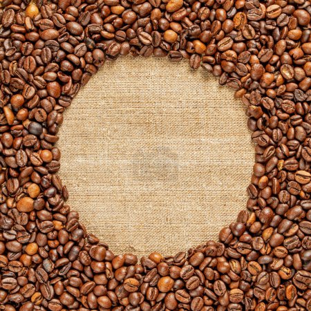 Photo for Frame of roasted coffee beans scattered around a burlap napkin inside. Place for text. - Royalty Free Image