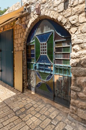 Photo for Large entrance doors with glass colored decorative stained-glass windows in a stone house on a quiet street in the old part of Safed city in northern Israel - Royalty Free Image