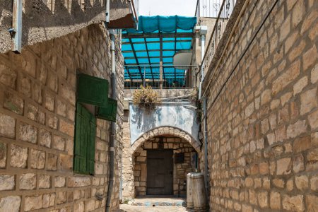 Photo for Quiet street with a stone pavement and stone walls of houses in the old part of Safed city in northern Israel - Royalty Free Image