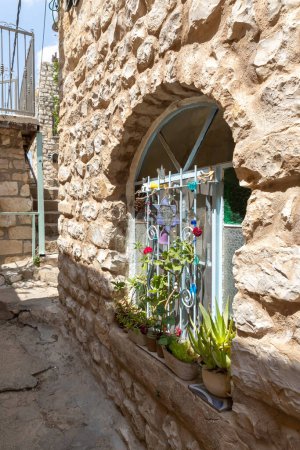 Photo for Decorative stained glass window with decorations and fresh flowers in an old residential building on a quiet street in the old part of Safed city in northern Israel - Royalty Free Image