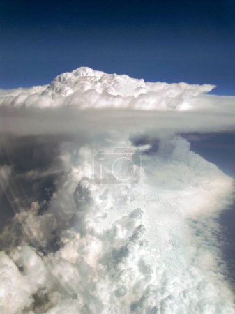 View from the window of an airplane flying at high altitude over mainland Europe to a bizarre mushroom shaped cloud