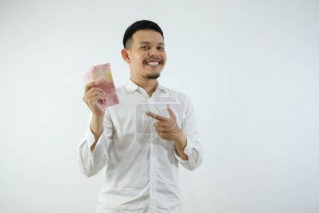 Foto de Adulto asiático hombre mostrando excitado expresión mientras apuntando a dinero que él hold - Imagen libre de derechos
