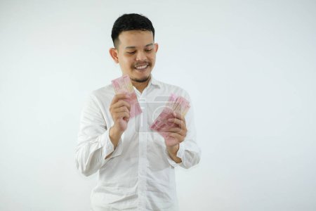 Téléchargez les photos : Adulte asiatique homme souriant heureux en comptant l'argent qu'il détient - en image libre de droit