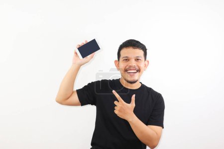 Téléchargez les photos : Adulte asiatique homme souriant heureux tout en montrant écran de téléphone portable vierge et pointant sur elle - en image libre de droit