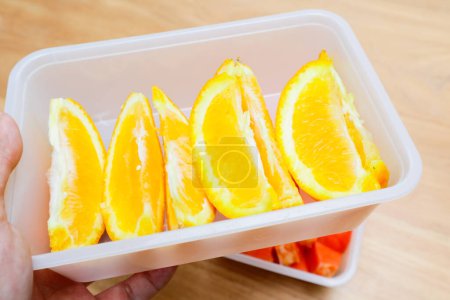 Photo for Sunkist orange fruit in a plastic container on a wooden table - Royalty Free Image