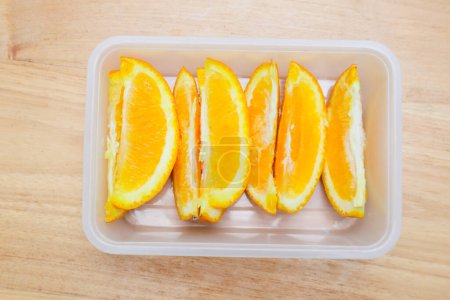 Sunkist orange fruit in a plastic container on a wooden table