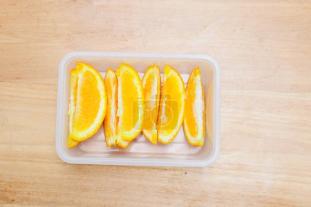 Photo for Sunkist orange fruit in a plastic container on a wooden table - Royalty Free Image
