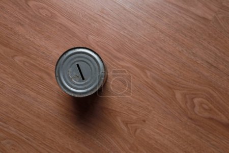 Metal piggy bank on wooden background, top view with copy space