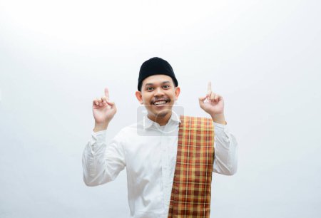 Téléchargez les photos : Asiatique musulman homme portant sarung pointant quelque chose avec son mains - en image libre de droit