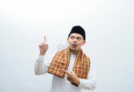 asiatischer muslimischer Mann, der Sarung trägt und etwas mit seinen Händen zeigt