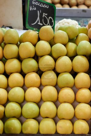 Montón de manzanas que se muestran en un mostrador de una tienda de frutas. Tiene una pizarra donde se especifica el precio que cuesta.