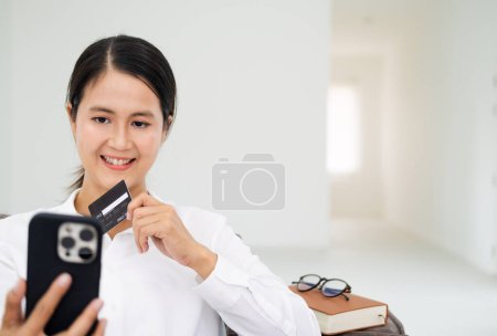 Foto de Mujer de mediana edad feliz sentado con tarjeta de crédito y teléfono inteligente - Imagen libre de derechos