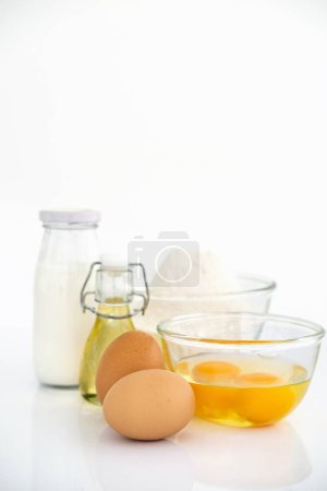 Foto de Harina de trigo con huevos, aceite y leche sobre la mesa. Mesa blanca Copyspace vista frontal - Imagen libre de derechos