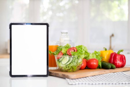 Laptop-Computer-Attrappe weißen Bildschirm auf vegetarischer gesunder Ernährung Gemüse Hintergrund. Online-Lebensmitteleinkauf Lieferung App Anzeigen Konzept, Kochbuch Ernährungsplan Ernährungsrezepte, Nahsicht.