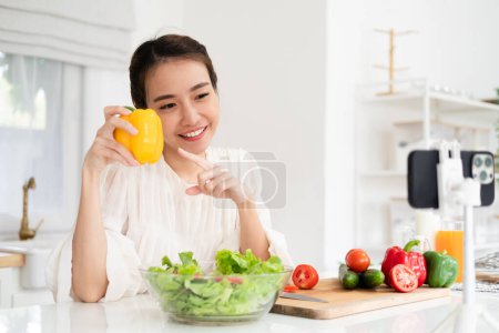 Foto de Mujer joven y alegre vlogging en el teléfono móvil acerca de la comida saludable y la cocina. Concepto de alimentación saludable y las redes sociales que influyen - Imagen libre de derechos