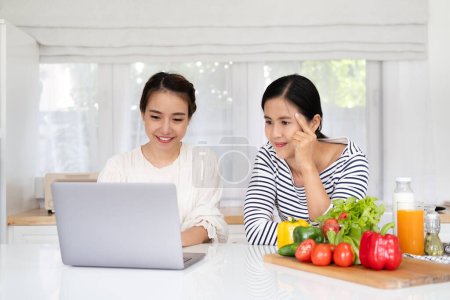 Foto de Las mujeres asiáticas preparan ingredientes para cocinar seguir curso de cocina en línea en el sitio web a través de tabletas. contenido de cocina en la tecnología de Internet para el concepto de estilo de vida moderno - Imagen libre de derechos