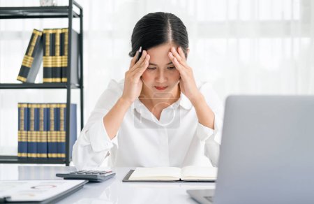 Foto de Las mujeres asiáticas están estresadas mientras trabajan en la computadora portátil, mujer de negocios asiática cansada con dolor de cabeza en la oficina, sentirse mal en el trabajo, espacio para copiar - Imagen libre de derechos