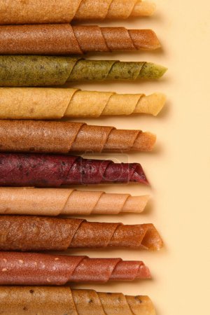 Photo for Paste. Pattern of various pastila fruit leather rolls with fruit on a beige background. Vertical. - Royalty Free Image