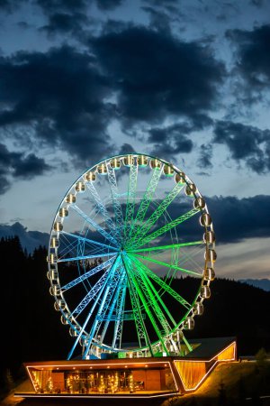 Grande roue illuminée dans la soirée.
