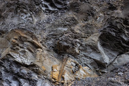 Cara del acantilado de Shabby envejecido y dividida por enormes grietas y capas