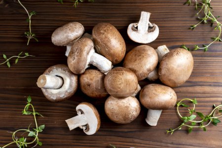 Raw champignon mushrooms in large quantities on a wooden dark table