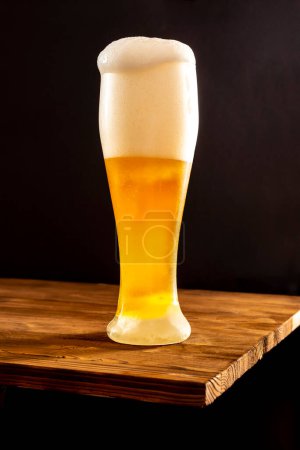 Photo for Light craft beer in a misted glass on a wooden table. - Royalty Free Image