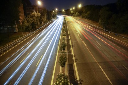 Téléchargez les photos : Traces de feux de véhicules circulant sur une autoroute éclairée par des lampadaires - en image libre de droit