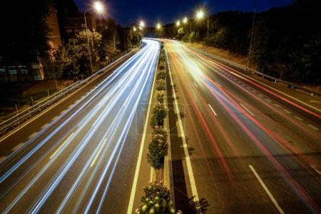 Téléchargez les photos : Traces de feux de véhicules circulant sur une autoroute éclairée par des lampadaires - en image libre de droit