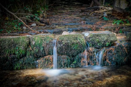 Langzeitbelichtungsfoto eines kleinen Wasserfalls in einem Bach
