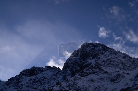 Foto de Bajo la vasta extensión de un cielo azul profundo, una imponente cima montañosa en Zakopane se erige como un testimonio de la grandeza de la naturaleza, su silueta envuelta en sombras y misterios de eones pasados.. - Imagen libre de derechos