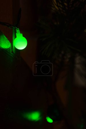 Foto de Bombilla verde solitaria: un faro de espíritu navideño en las sombras Iluminación verde suave de una sola luz navideña Luz navideña caprichosa: un toque de verde en la noche - Imagen libre de derechos