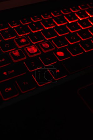 Red-backlit keyboard with visible signs of use, ideal for gaming-related content. Hardcore gaming at its best: well-used keyboard with intense red backlighting.