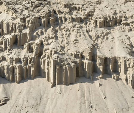 Erosionsgeschnitzte Sandformationen, die an eine Bergkette im Miniaturformat erinnern. Komplizierte Sandburgruinen, die durch natürliche Verwitterungsprozesse entstanden sind. Die zarte Kunst der Natur: windgeformte Säulen im sandigen Gelände.