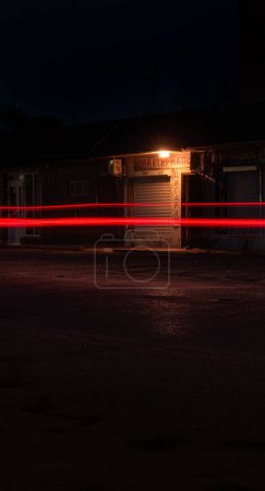 Nächtliche Stadtlandschaft mit Leuchtreklamen für Alkohol und Zigaretten. Szene aus dem Nachtleben der Stadt, beleuchtet von Neonwerbung für Alkohol und Tabakprodukte. Neonglühen aus einem örtlichen Geschäft, das Spirituosen und Rauch in einer ruhigen Stadt verkauft.