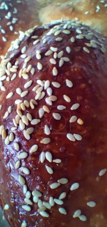 Foto de Primer plano de un pan recién horneado espolvoreado con semillas de sésamo, mostrando la corteza dorada y la textura seductora, perfecto para un regalo casero. - Imagen libre de derechos