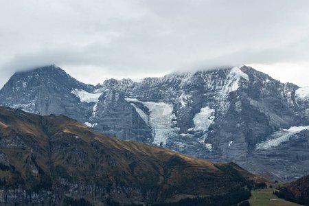 Photo for Snowy Alp mountains in the Switzerland. Beautiful view on snow-covered mountain peaks. Autumn in Murren. Cloudy sky - Royalty Free Image