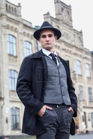 Téléchargez les photos : Séance photo pour hommes dans un costume à carreaux classique et un chapeau sur fond de vieil immeuble. - en image libre de droit