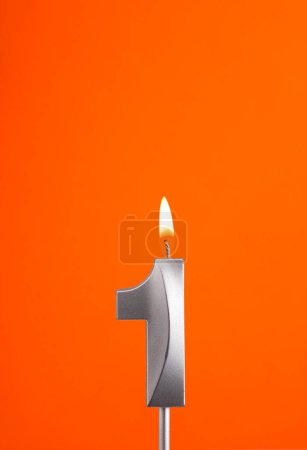 Téléchargez les photos : Numéro 1 - Bougie d'anniversaire brûlante sur fond mousseux orange - en image libre de droit