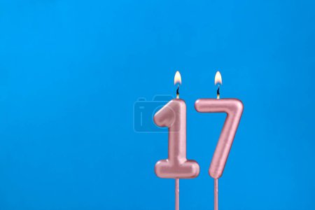 Número 17 - Vela de aniversario ardiente sobre fondo azul espumoso